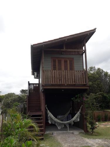 una casa con una hamaca delante en Cabana aconchegante Praia do Rosa Rosamarina, en Imbituba