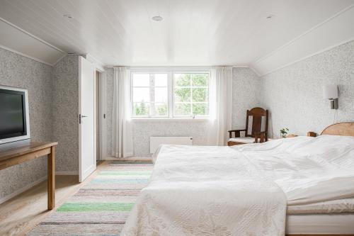 a white bedroom with a bed and a television at Solar Lake Cottage in Jönköping