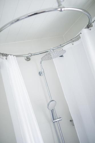 a shower head in a bathroom with a shower curtain at Solar Lake Cottage in Jönköping