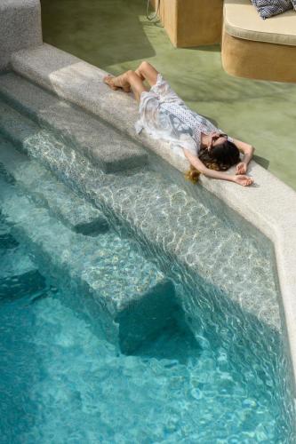 a woman laying on the edge of a swimming pool at Potamos Luxury House, Private Pool, Santorini in Éxo Goniá