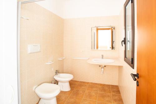 a white bathroom with a toilet and a sink at Villaggio Camping Oasi in Vieste