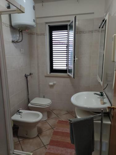 a bathroom with a white toilet and a sink at Bougainvillea in Marina di Modica
