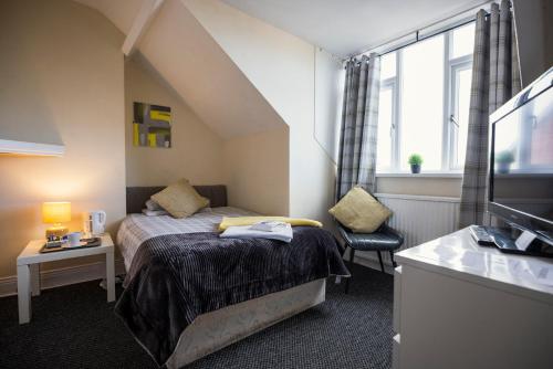 ein kleines Schlafzimmer mit einem Bett und einem Fenster in der Unterkunft Dunes Hotel in Whitley Bay