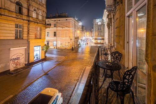 una calle de la ciudad por la noche con una mesa y sillas en el balcón en Classic Royal central apartment. Balcony and A/C, en Leópolis