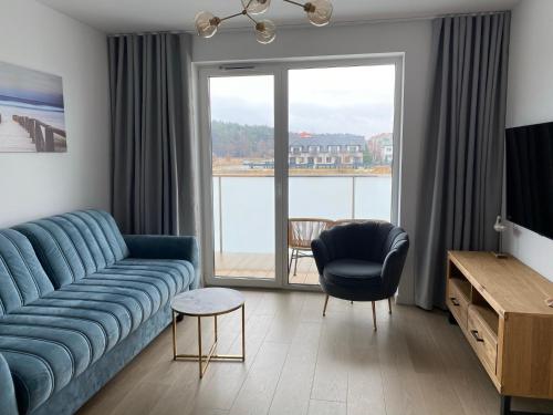 a living room with a blue couch and a large window at Apartament Coral in Grzybowo