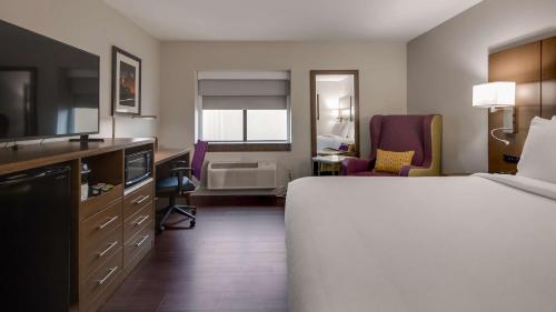a hotel room with a bed and a desk and chairs at Best Western Huntsville in Huntsville