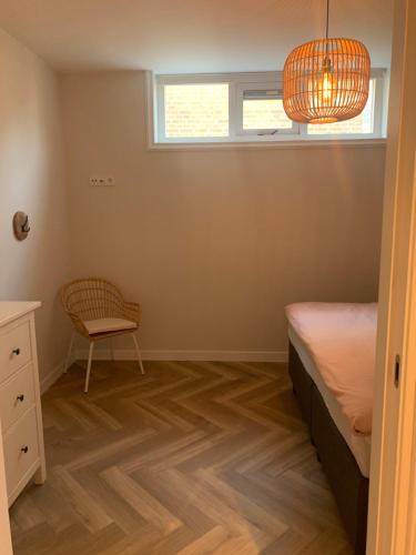 a bedroom with a bed and a chair and a window at 'T Hûske 66 in Burum