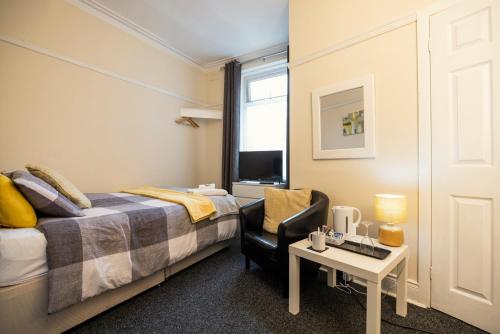 a bedroom with a bed and a chair and a table at Dunes Hotel in Whitley Bay