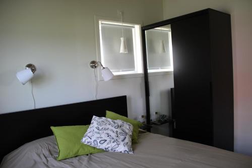 a bedroom with a bed with a black headboard and two windows at Lakeview Houses Sweden in Falun