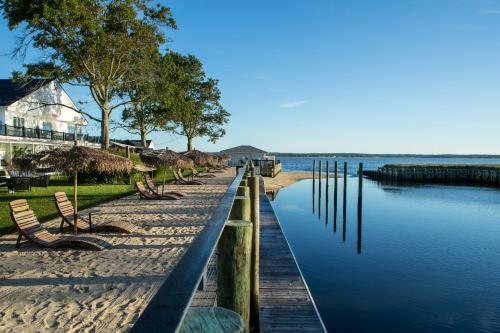a dock with chairs on the beach next to the water at Aqua by American Beech - Adults Only in Aquebogue
