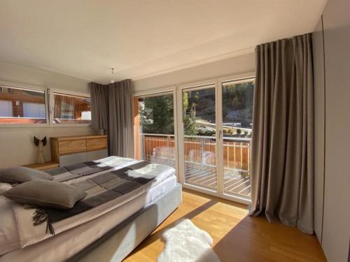 a bedroom with a large bed and a balcony at Luxury Apartment Romaine 1st floor in Saas-Fee
