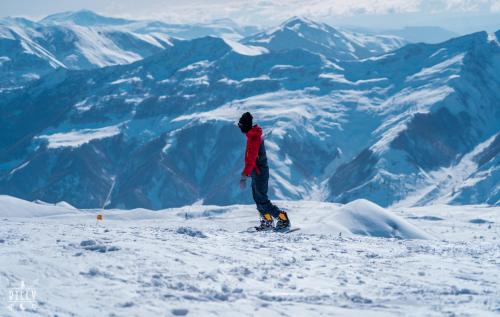 a person on a snowboard on top of a mountain at New Gudauri NG Rooms in Gudauri