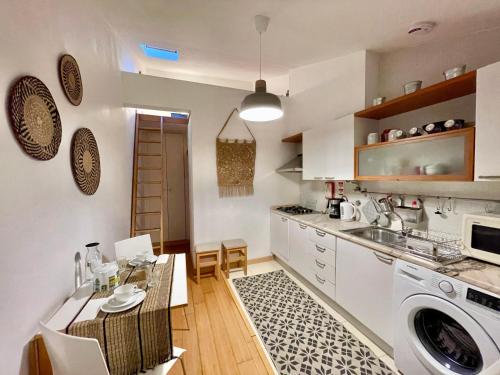 uma cozinha com uma mesa, um lavatório e uma máquina de lavar roupa em Casa Coração do Bairro em Lisboa