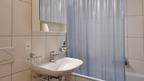 baño con lavabo y cortina de ducha azul en Snowfun B Penthouse, en Saas-Fee