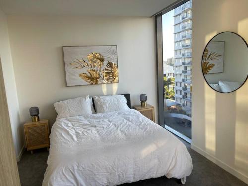 een slaapkamer met een wit bed en een spiegel bij Lovely 2 Bedroom Executive Apartment in Brisbane