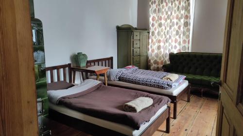 two twin beds in a room with a couch at Stare Dechy in Wschowa