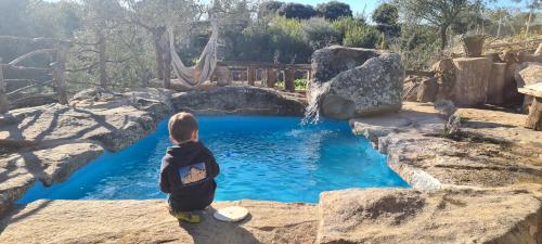 un bebé sentado en una roca frente a un charco de agua en Casa Rural Therma Agreste, en Bermellar