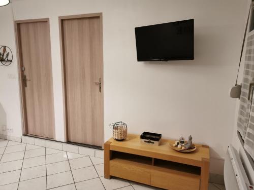 a living room with a table and a tv on a wall at Au Petit Bonheur Malouin in Malo-les-Bains