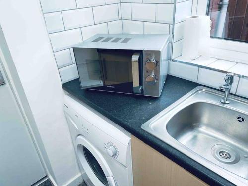 a small kitchen with a sink and a microwave at Homely 3 Bed Town house in Coventry City Centre in Coventry