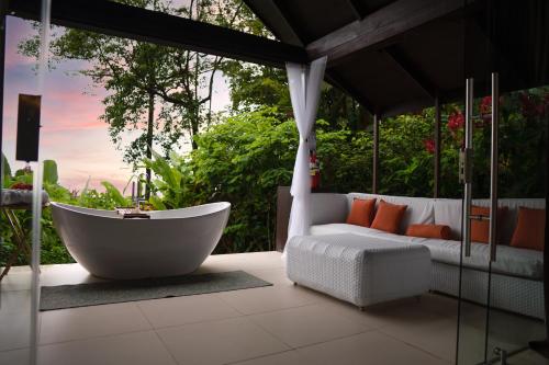 a bath tub sitting on a patio with a couch at Oxygen Jungle Villas & Spa in Uvita