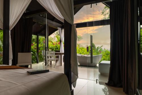 1 dormitorio con bañera y 1 cama con vistas en Oxygen Jungle Villas & Spa en Uvita
