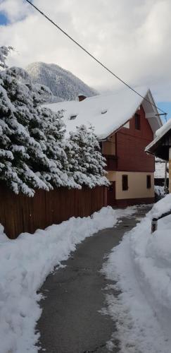 a snow covered road next to a house with a fence at Zajček Apartma in Mojstrana