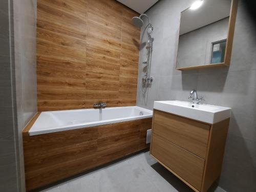 a bathroom with a bath tub and a sink at Apartamenty Lubin -Amaretto- in Lubin