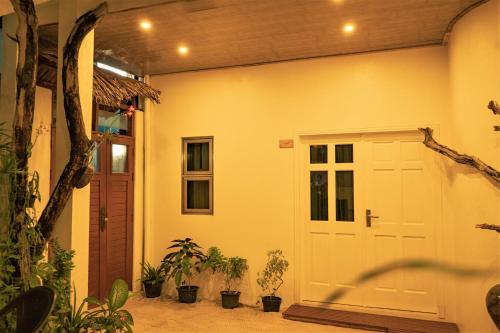 a garage with a white door and plants on the side at Nala Island Village in Maafushi