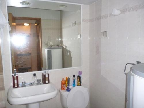 ein Badezimmer mit einem Waschbecken, einem WC und einem Spiegel in der Unterkunft Departamento Frente al Mar in Concón