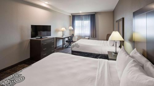 a hotel room with two beds and a flat screen tv at Baymont by Wyndham Moses Lake in Moses Lake