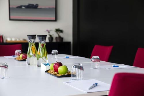 a long white table with red chairs and wine bottles at Park Inn by Radisson Dubai Motor City in Dubai