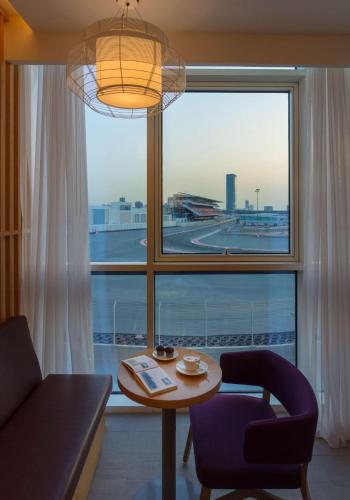 a living room with a table and a window with an airport at Park Inn by Radisson Dubai Motor City in Dubai
