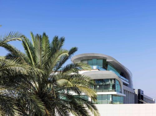a building with a palm tree in front of it at Radisson Blu Hotel, Kuwait in Kuwait