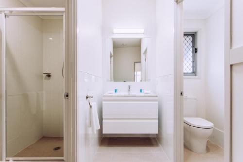 a white bathroom with a toilet and a sink at Woolgoolga Beach Holiday Park in Woolgoolga