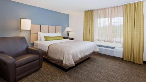a bedroom with a bed and a chair and a window at Sonesta Simply Suites Dallas Richardson in Dallas