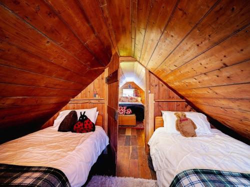 1 dormitorio con 2 camas en una habitación de madera en Portobello Settler's Cottage en Portobello