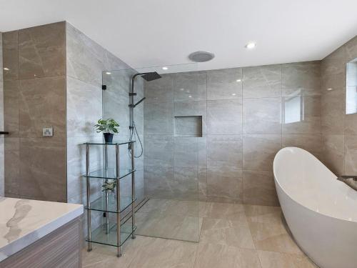 La salle de bains est pourvue d'une douche, d'une baignoire et d'un lavabo. dans l'établissement Toukley Waterfront House, à Toukley
