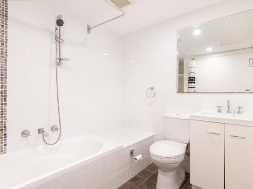 een witte badkamer met een toilet, een bad en een wastafel bij Shores G1 on Head Street close to Main Beach in Forster