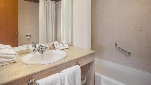 uma casa de banho com um lavatório, um espelho e uma banheira em Hotel RH Sol em Benidorm