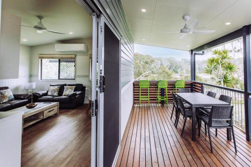a living room with a balcony with a table and chairs at Woolgoolga Lakeside Holiday Park in Woolgoolga