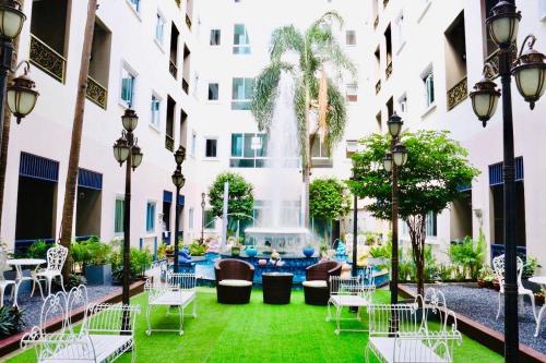 a courtyard with chairs and a fountain in a building at Napheera Royal Tel in Ban Khlong Bang Krathiam