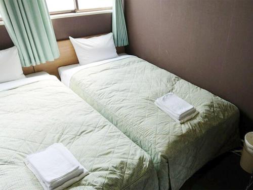 two beds sitting next to each other in a room at City Inn Nishi Tanabe in Osaka