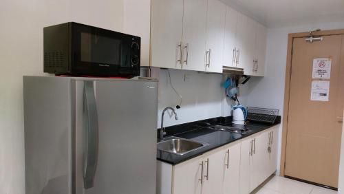 a kitchen with a sink and a microwave on top of a refrigerator at MSH property Sea Residences MOA Pasay City by Queennie in Manila