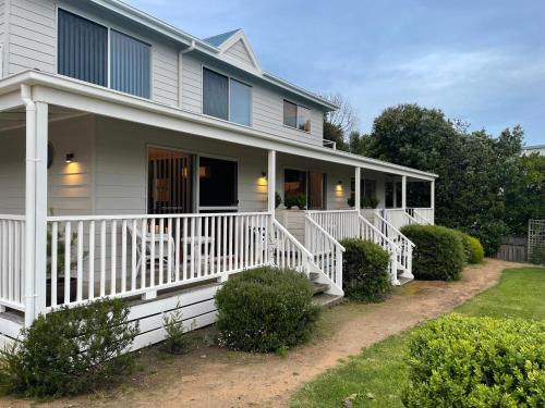 a white house with a white porch and bushes at Skippers Apollo Bay in Apollo Bay