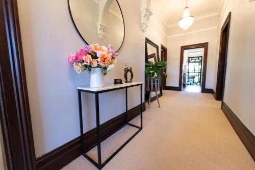 a hallway with a mirror and flowers in a vase at Avoca House - Gorgeous Federation Home in Mudgee