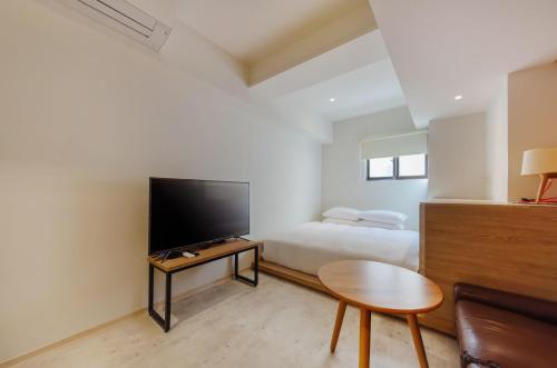 1 dormitorio con 1 cama, TV y mesa en Popinn en Anping