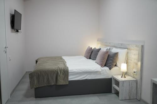 a white bedroom with a large bed and a television at Koghbatsi Aparthotel in Yerevan