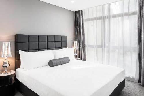 a bedroom with a large white bed and a window at Meriton Suites Chatswood in Sydney
