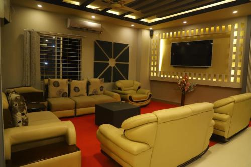 a living room with couches and a flat screen tv at The Grand Mafi Hotel & Suites in Sylhet