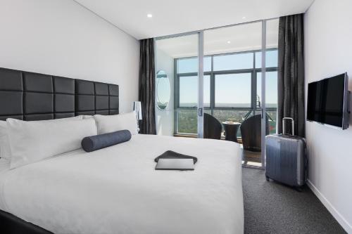 a hotel room with a bed and a large window at Meriton Suites Chatswood in Sydney